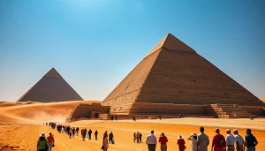 Tourists marvel at the magnificent piraminds under a bright blue sky.